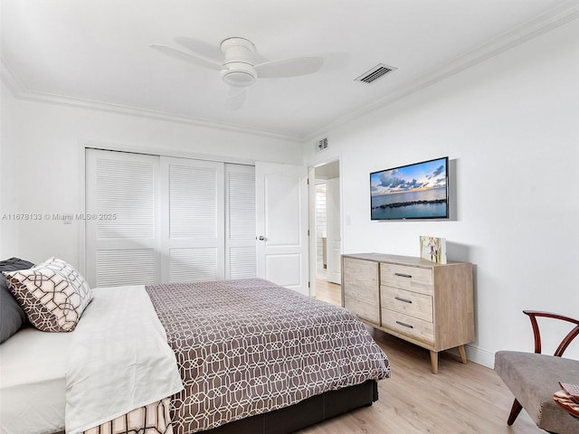 bedroom with visible vents, light wood-style flooring, ceiling fan, ornamental molding, and a closet