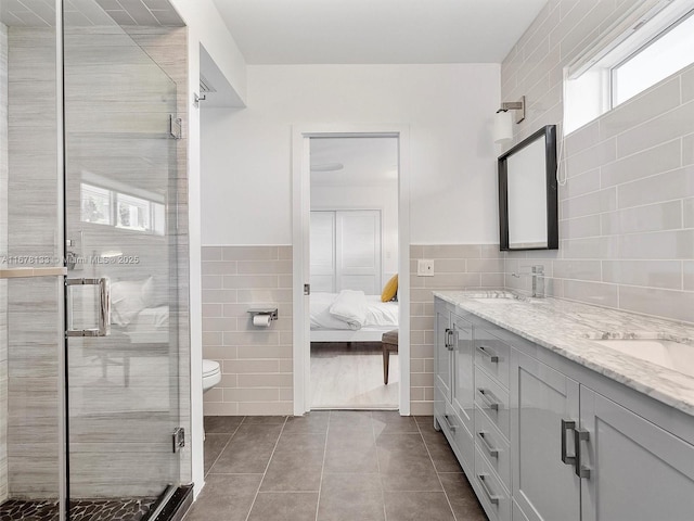 bathroom with tile patterned floors, a stall shower, tile walls, and a sink