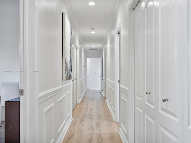 hall with a wainscoted wall, recessed lighting, ornamental molding, a decorative wall, and light wood-type flooring