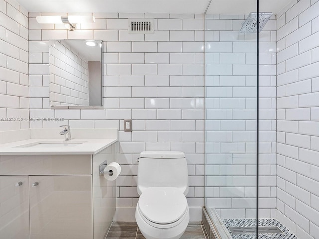 full bathroom with vanity, visible vents, walk in shower, tile walls, and toilet