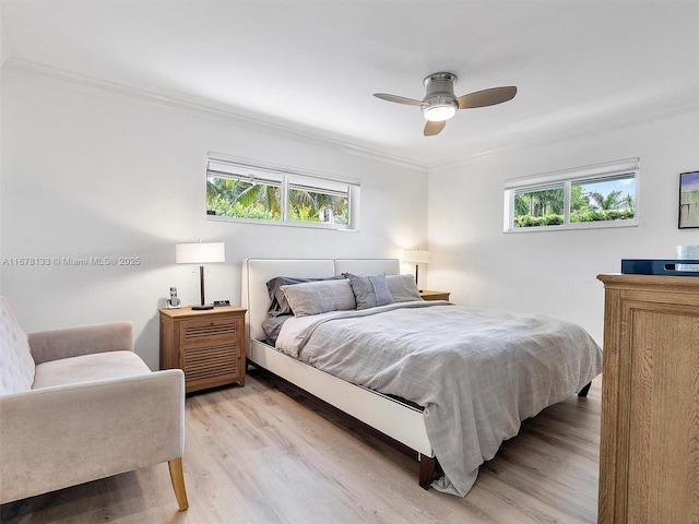 bedroom with a ceiling fan, crown molding, multiple windows, and light wood-style floors