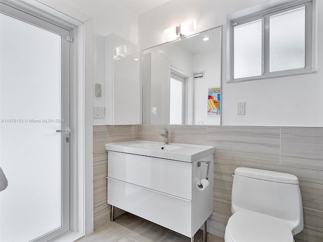 bathroom featuring vanity, toilet, tile walls, and tile patterned flooring