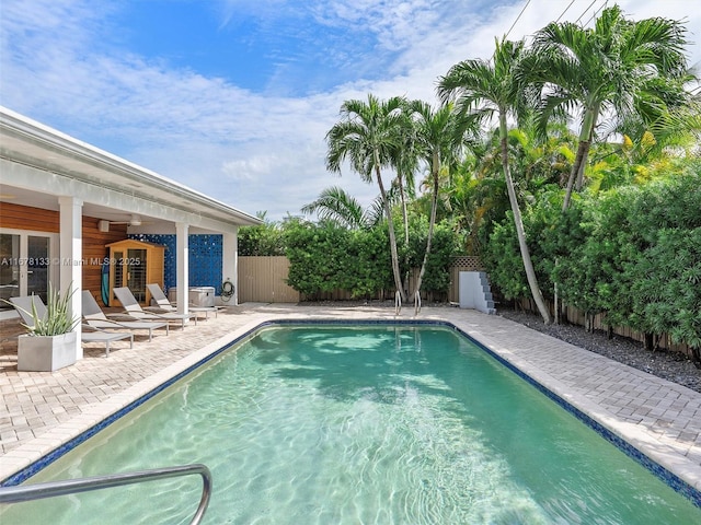 outdoor pool with a patio area and a fenced backyard