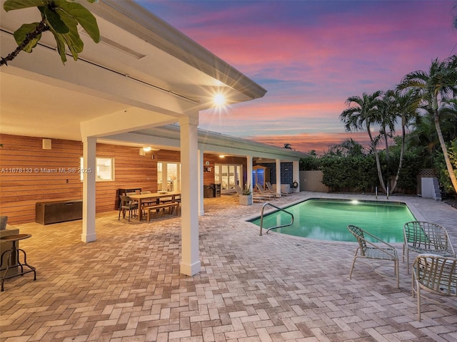 pool at dusk with a patio area, a fenced in pool, outdoor dining area, and fence