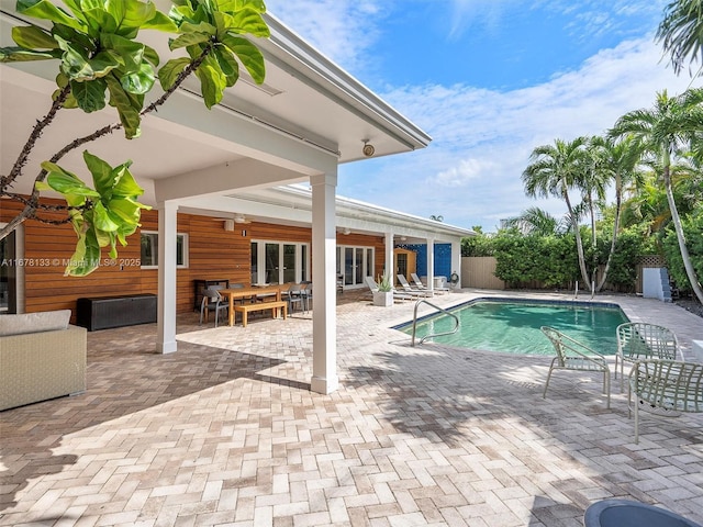 view of swimming pool featuring fence, french doors, a fenced in pool, ceiling fan, and a patio area