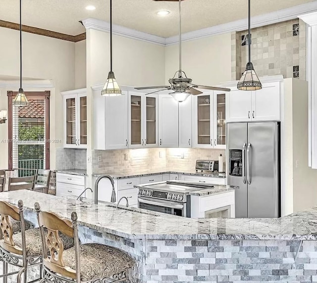 kitchen with a breakfast bar area, pendant lighting, white cabinetry, and stainless steel appliances