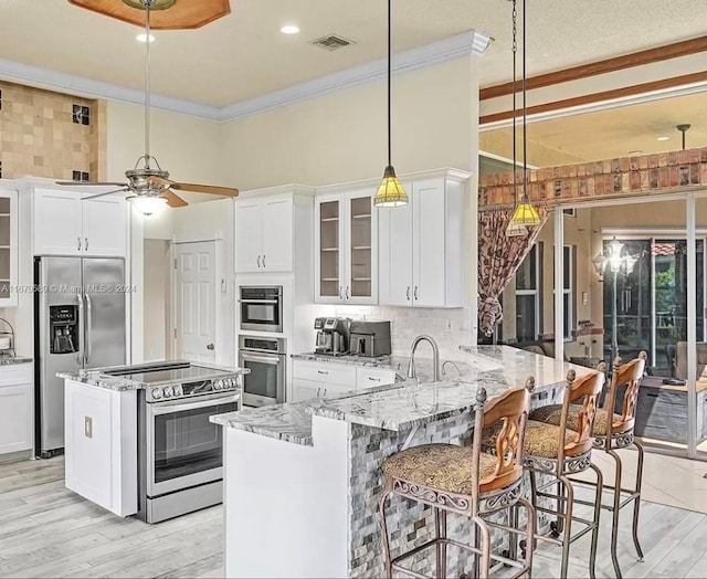 kitchen featuring light stone countertops, kitchen peninsula, stainless steel appliances, and white cabinets