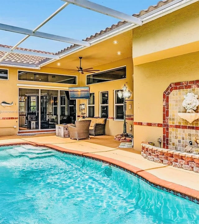 view of pool featuring a patio, an outdoor hangout area, ceiling fan, and glass enclosure