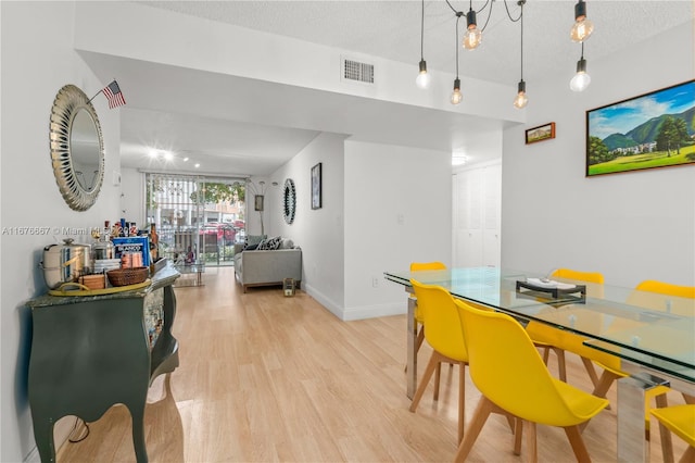 dining area with light hardwood / wood-style flooring and a textured ceiling