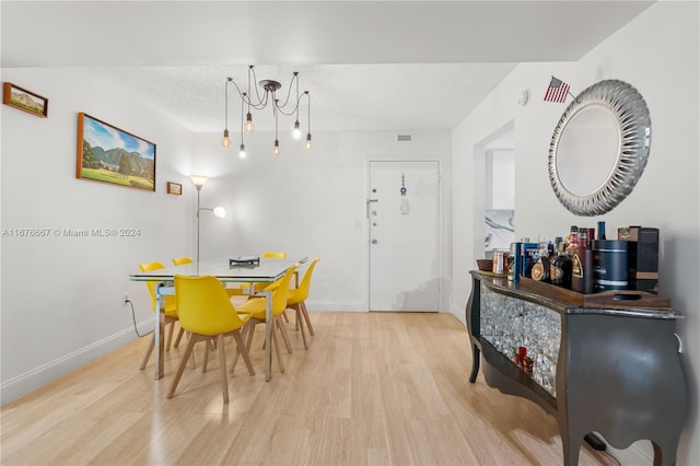 dining area with light hardwood / wood-style floors and a textured ceiling