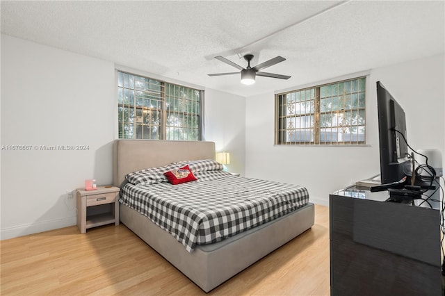 bedroom featuring light hardwood / wood-style flooring, a textured ceiling, and ceiling fan