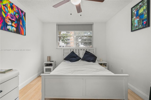 bedroom featuring a textured ceiling, light wood-type flooring, and ceiling fan