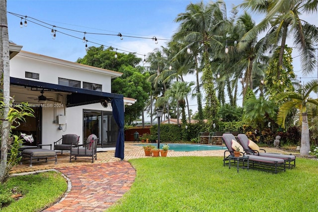 view of yard featuring a patio, ceiling fan, and a fenced in pool