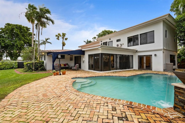 view of pool with a patio area, pool water feature, and a sunroom