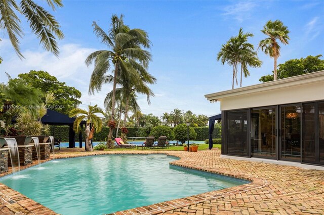 view of swimming pool featuring a sunroom, pool water feature, and a patio area