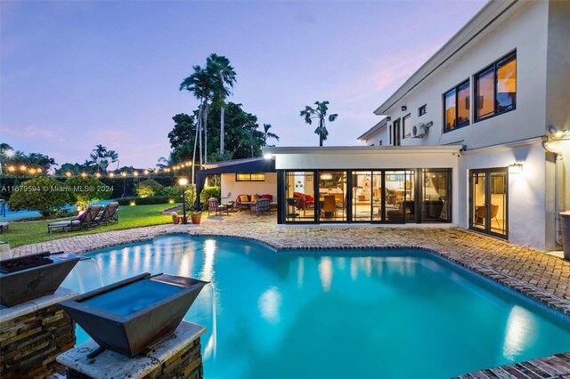 pool at dusk featuring a patio and an outdoor living space