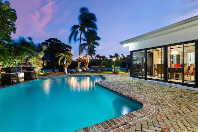 pool at dusk featuring a patio