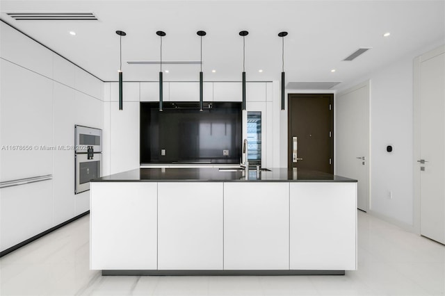 kitchen with white cabinets, a center island with sink, pendant lighting, and sink