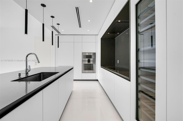 kitchen with pendant lighting, white cabinets, double oven, sink, and light tile patterned floors