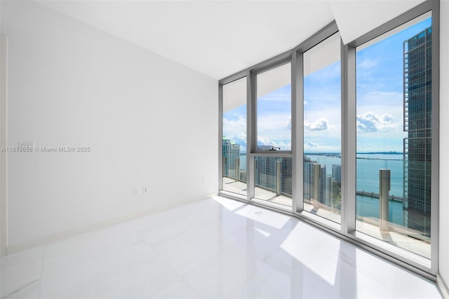 empty room with a water view, tile patterned flooring, and floor to ceiling windows