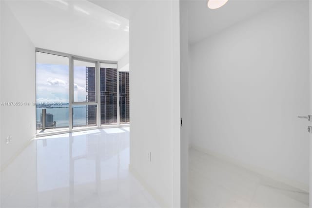 tiled empty room featuring a wall of windows and a water view