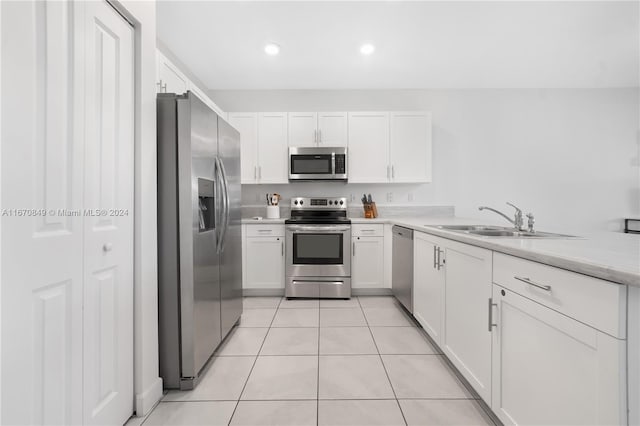 kitchen featuring appliances with stainless steel finishes, sink, kitchen peninsula, white cabinetry, and light tile patterned floors