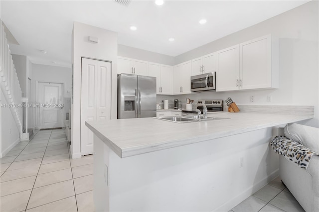 kitchen featuring kitchen peninsula, white cabinets, stainless steel appliances, and light tile patterned floors