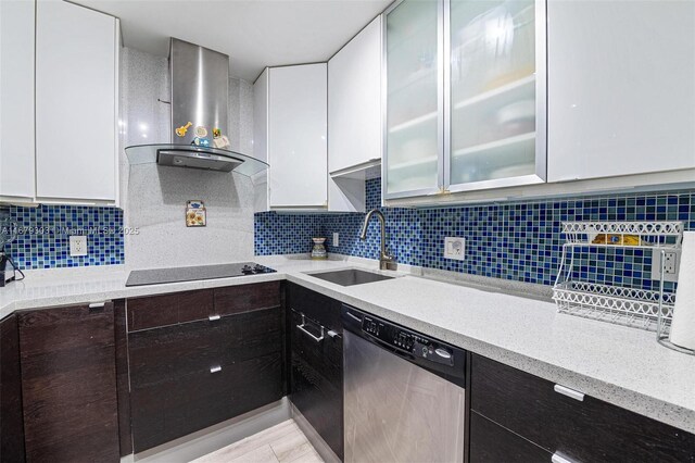 kitchen featuring black electric stovetop, wall chimney range hood, sink, stainless steel dishwasher, and white cabinets