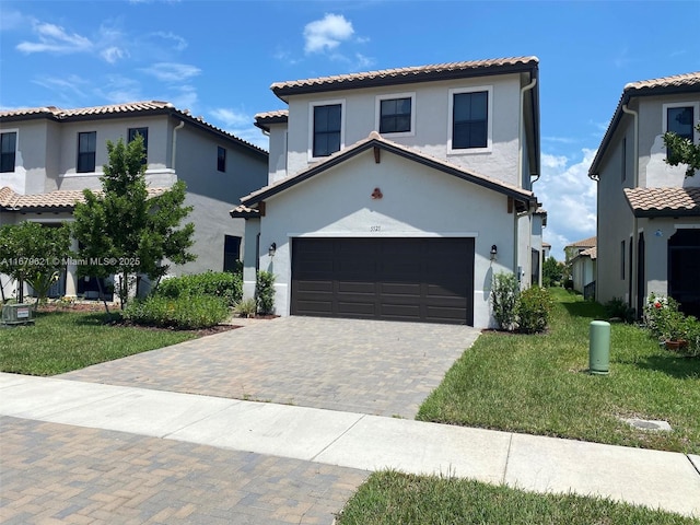 mediterranean / spanish-style home featuring a garage, a tiled roof, decorative driveway, stucco siding, and a front lawn