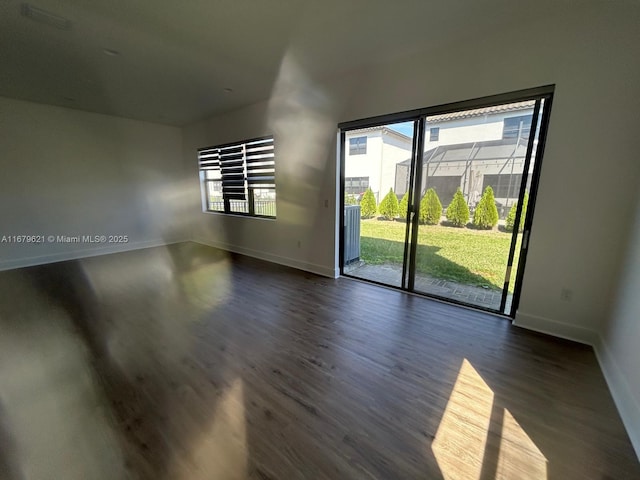 spare room with dark wood-type flooring and baseboards