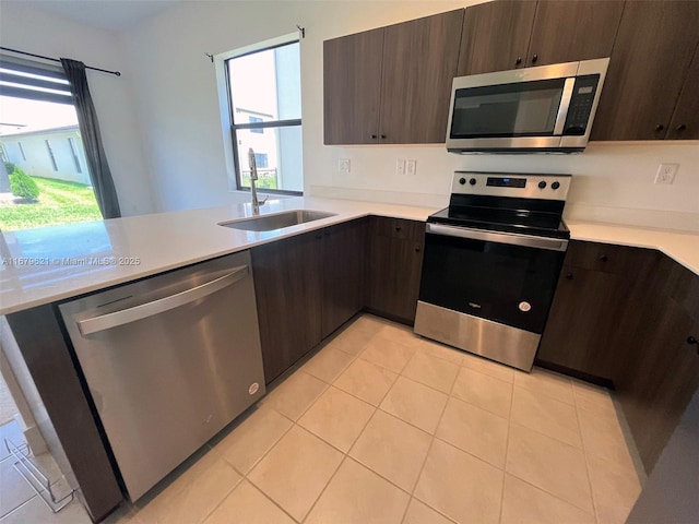 kitchen featuring a sink, stainless steel appliances, light countertops, and dark brown cabinetry