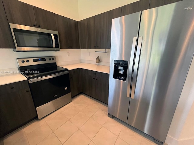 kitchen with light tile patterned floors, dark brown cabinetry, stainless steel appliances, light countertops, and modern cabinets