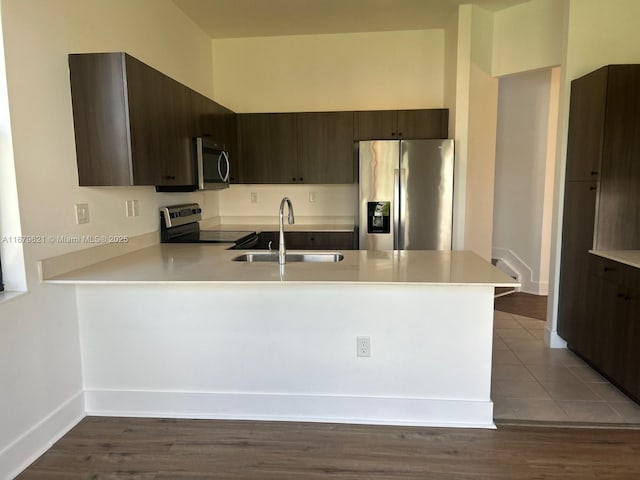 kitchen with a peninsula, appliances with stainless steel finishes, light countertops, and a sink