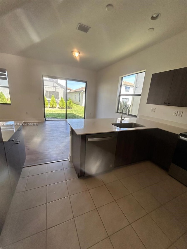 kitchen with light countertops, visible vents, light tile patterned flooring, a sink, and dishwashing machine