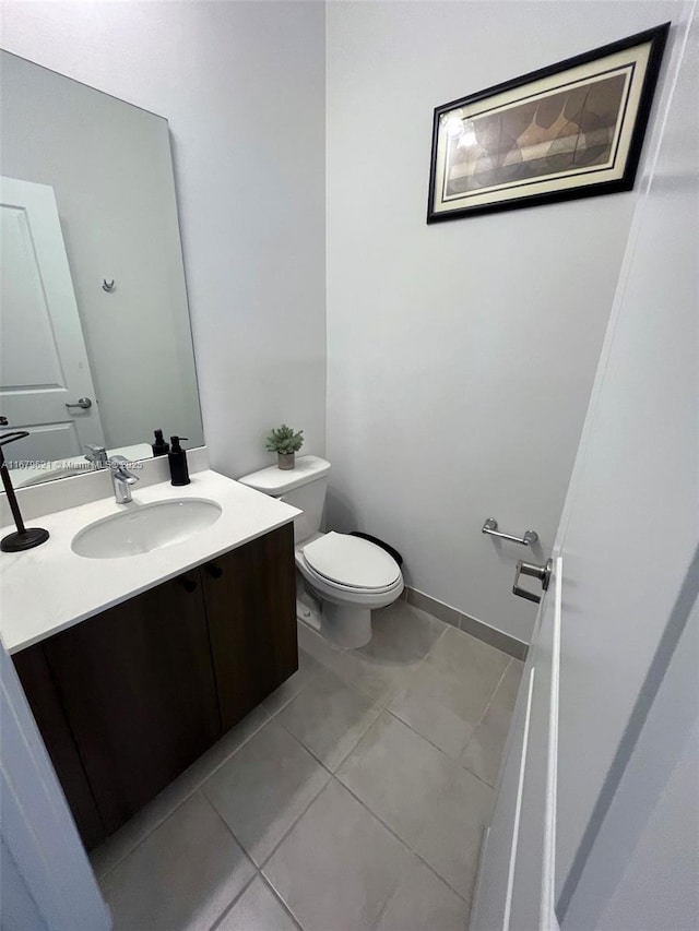 bathroom featuring toilet, tile patterned floors, baseboards, and vanity