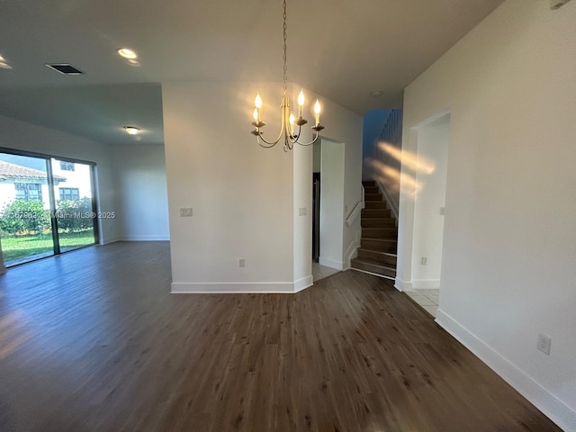 empty room with a notable chandelier, stairs, baseboards, and dark wood-style flooring