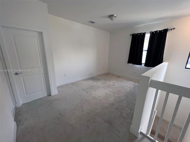 empty room featuring baseboards, visible vents, and light colored carpet