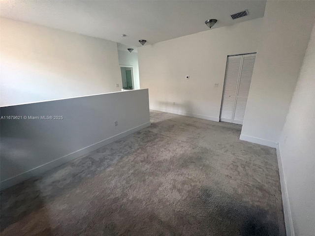 spare room featuring carpet floors, visible vents, and baseboards