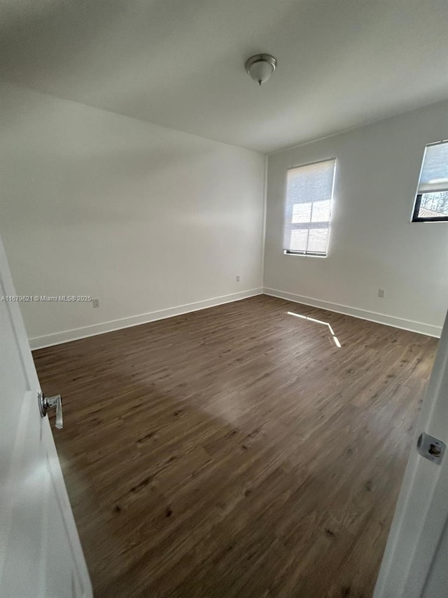 spare room with dark wood-style floors and baseboards