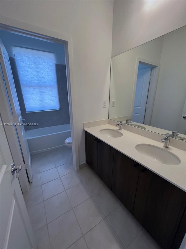 full bath featuring double vanity, a sink, toilet, and tile patterned floors