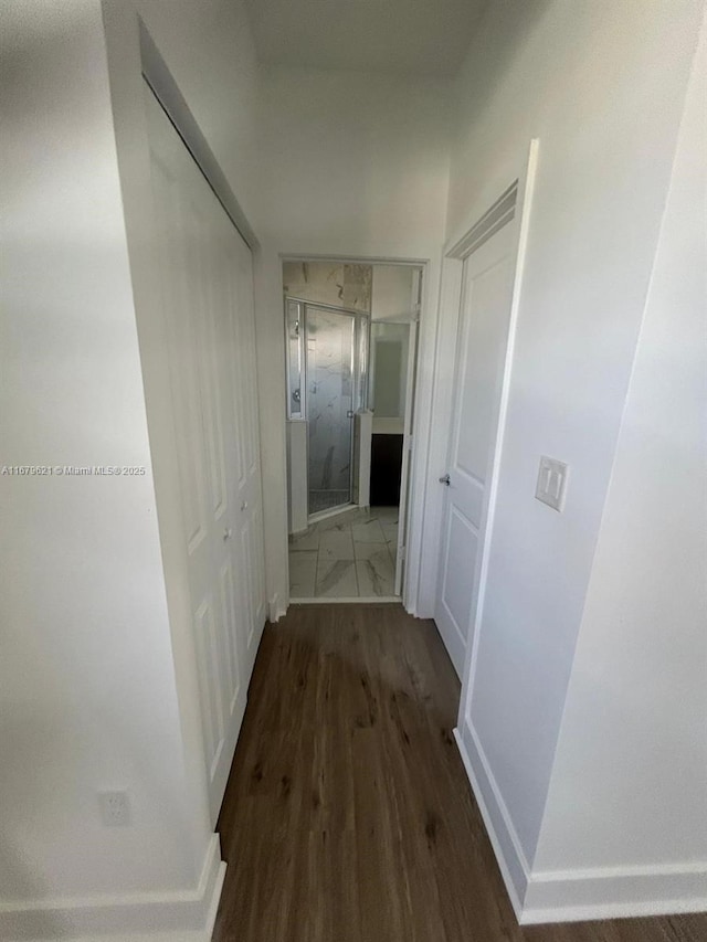 corridor featuring dark wood finished floors and baseboards