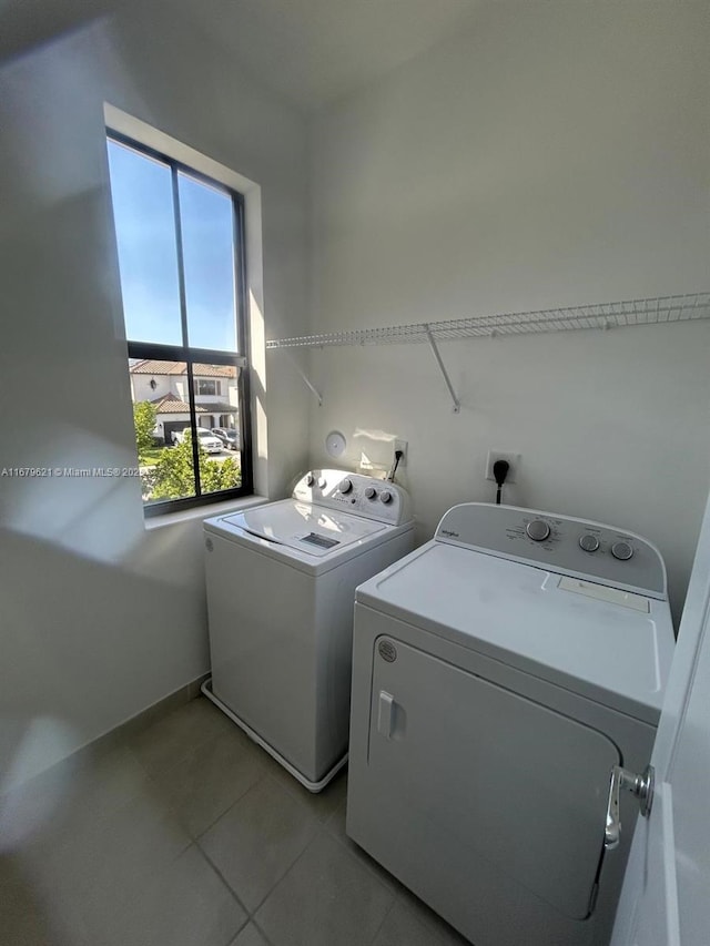 clothes washing area with laundry area, light tile patterned floors, and washer and clothes dryer