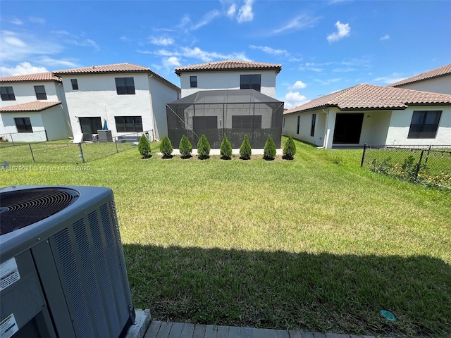 view of yard with central air condition unit, glass enclosure, and fence