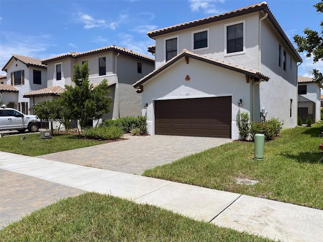 mediterranean / spanish home with a tiled roof, a front lawn, decorative driveway, and stucco siding