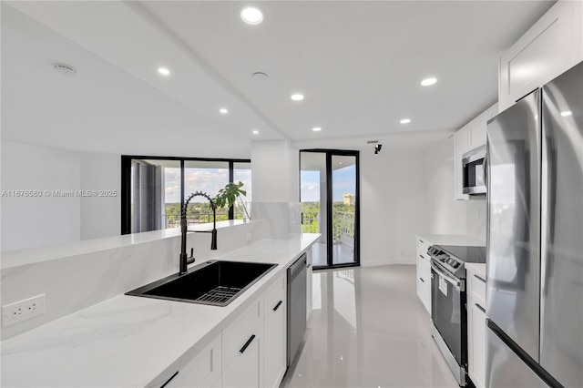 kitchen with light stone countertops, sink, white cabinets, and stainless steel appliances