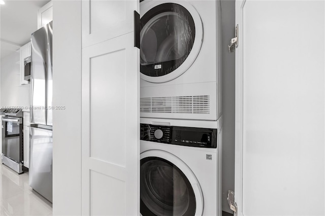 laundry room featuring stacked washer and dryer and light tile patterned flooring