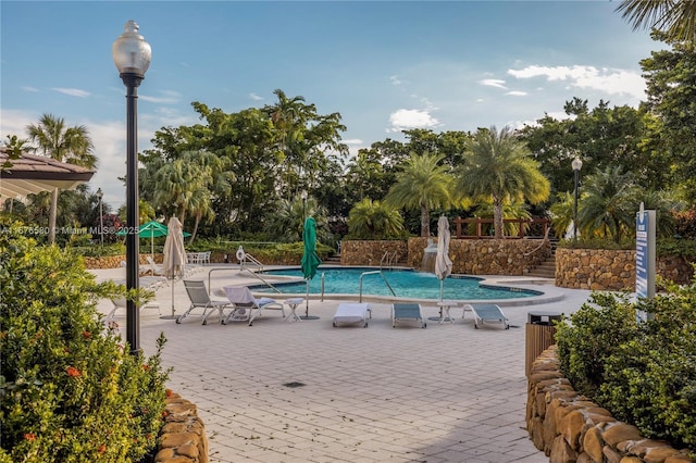 view of swimming pool with pool water feature and a patio area