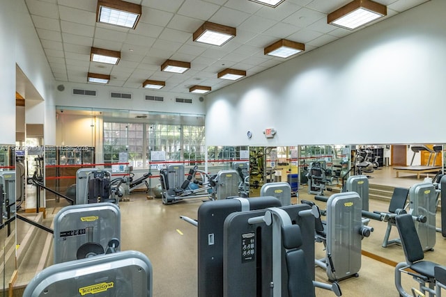 exercise room featuring a high ceiling and a drop ceiling