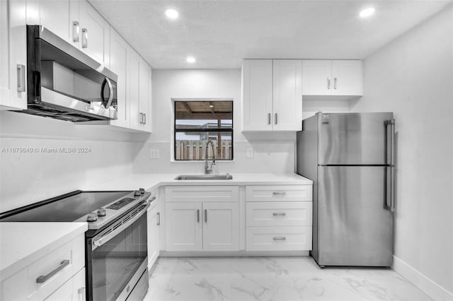 kitchen featuring white cabinets, stainless steel appliances, sink, and a textured ceiling