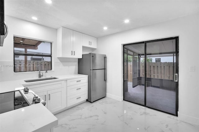 kitchen with stainless steel appliances, a wealth of natural light, and white cabinets